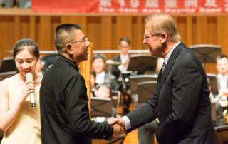 David Maslanka shakes Li Fangfang's hand after a performance of Symphony No. 4 by the Beijing Wind Orchestra at the National Center for the Performing Arts.