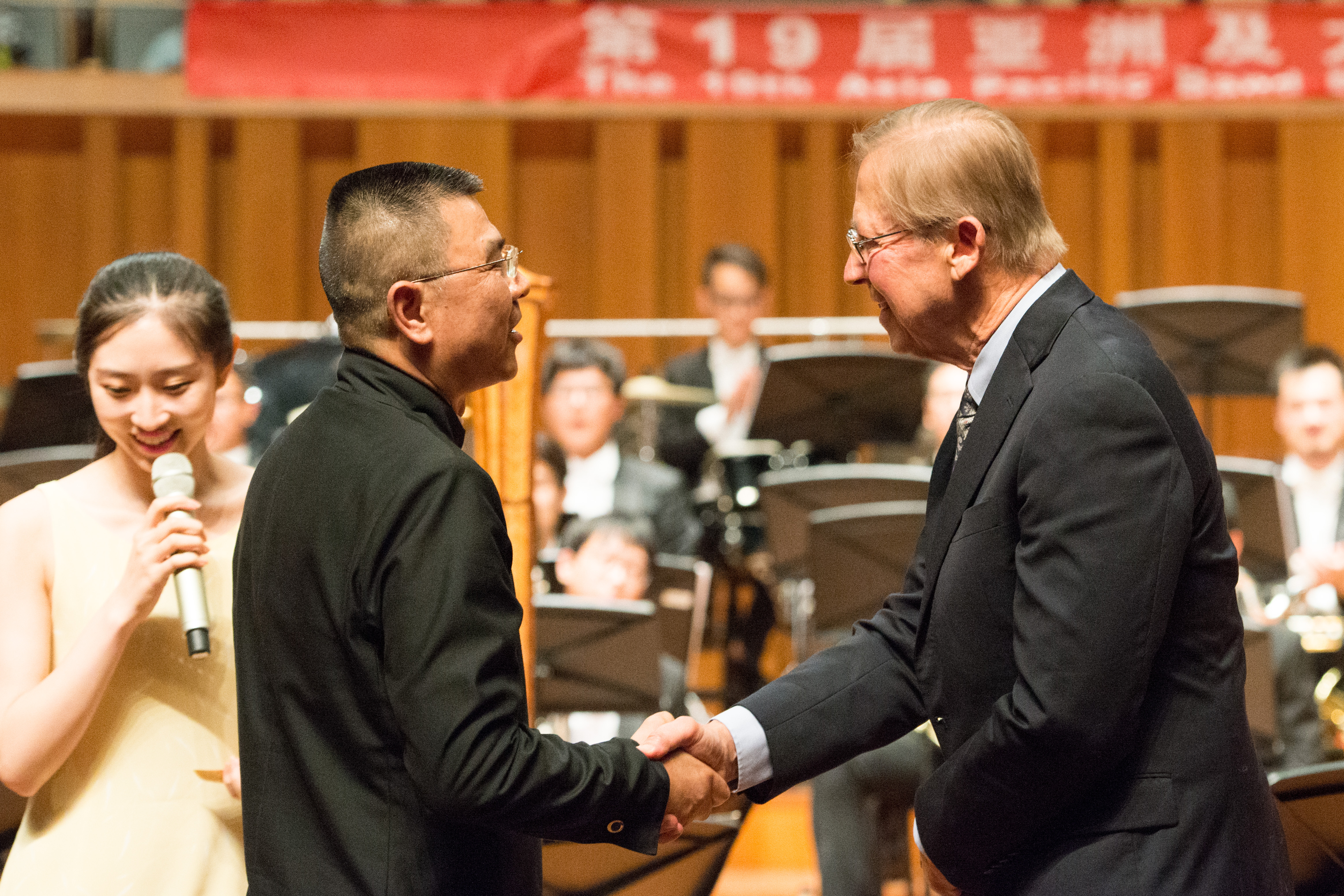 David Maslanka shakes Li Fangfang's hand after a performance of Symphony No. 4 by the Beijing Wind Orchestra at the National Center for the Performing Arts.